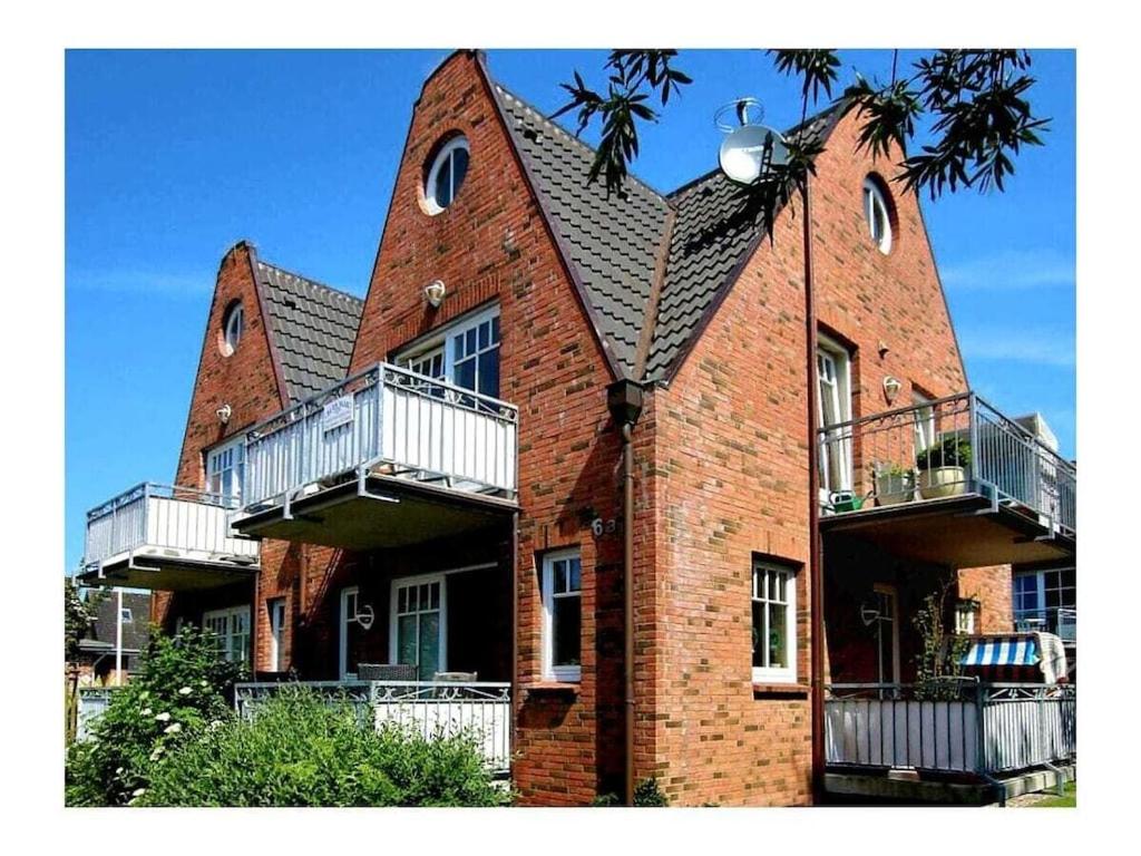 a large red brick building with balconies on it at Holiday apartment in Wyk with swimming pool in Wyk auf Föhr