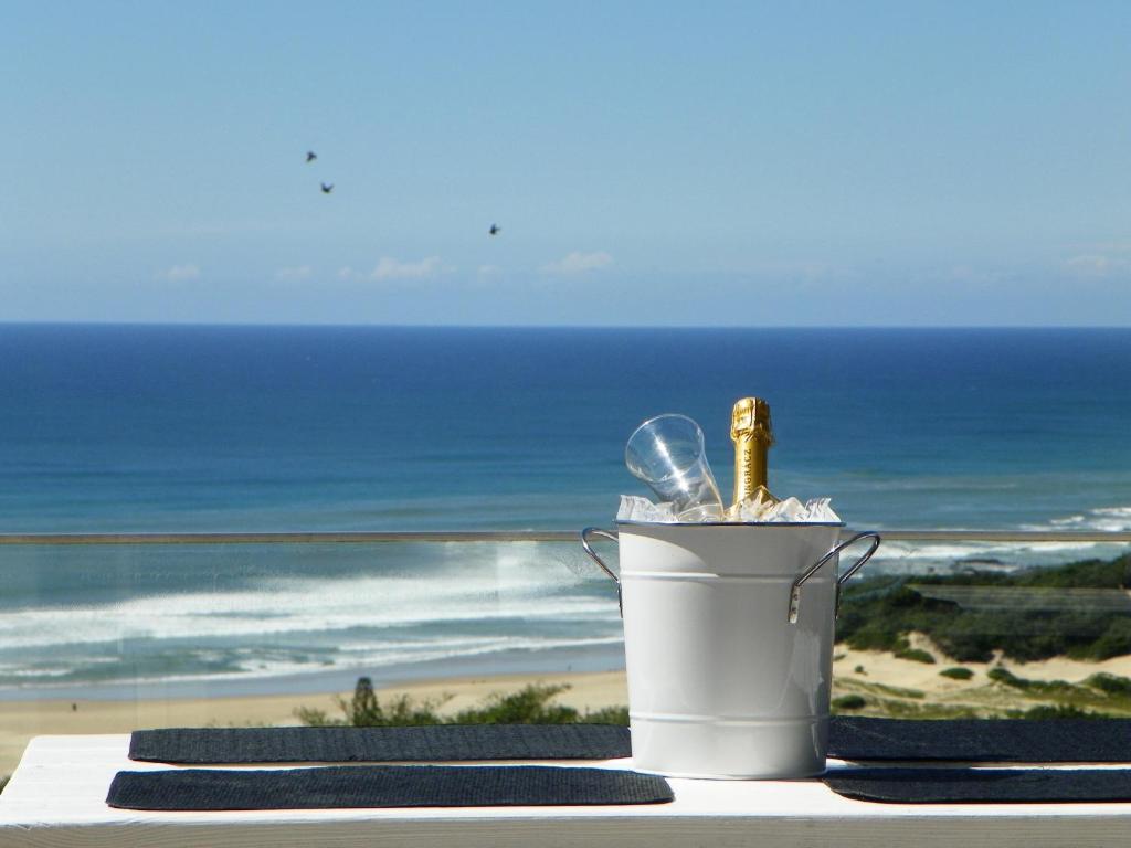 Una botella de champán en un cubo sobre una mesa con vistas al océano. en Cintsa View, en Chintsa