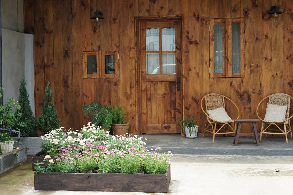 a wooden house with two chairs and a table and flowers at Maison De Oliu in Ấp Thiện Lập