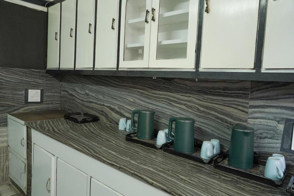 a kitchen counter with white cabinets and green cups at city centre luxury villa in Jammu