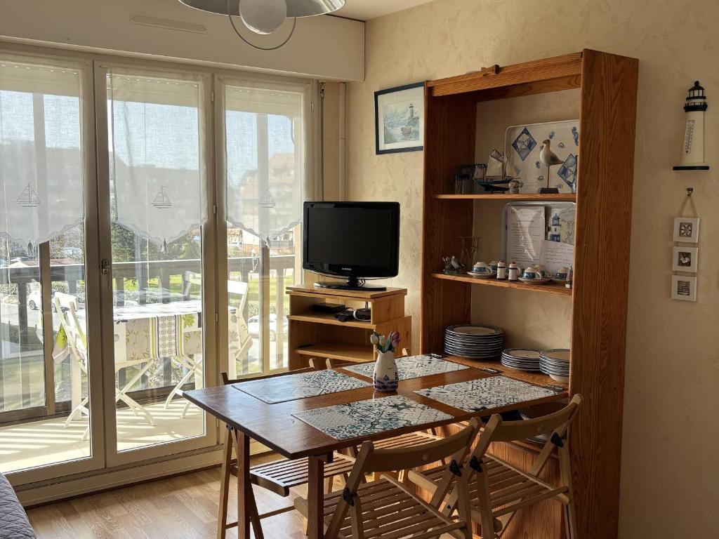 un salon avec une table et une télévision dans l'établissement Charmant 2 pièces avec loggia à deux pas de la plage, parking, tout équipé - FR-1-712-38, à Villers-sur-Mer