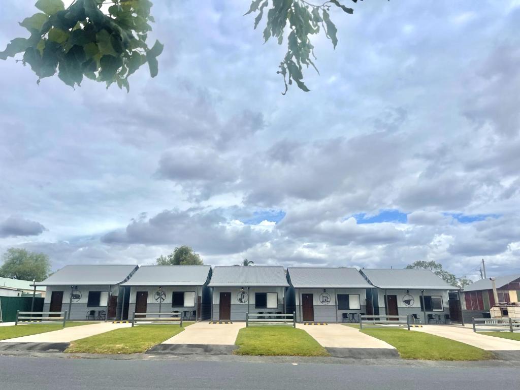 een schoolgebouw met een bewolkte lucht op de achtergrond bij Cooper's Cottages in Lightning Ridge
