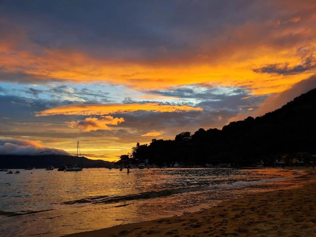 a sunset on a beach with the sun setting at Suíte 1 - Vila dos Pescadores in Angra dos Reis