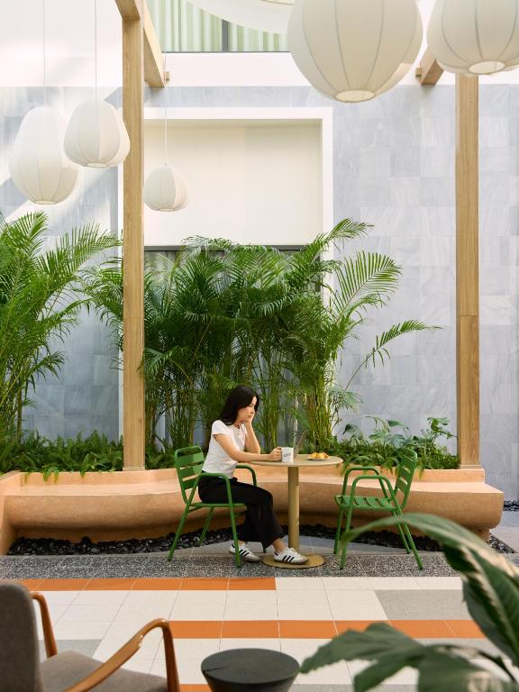 A planted lobby nook with small café tables beneath oversized pendant lights.