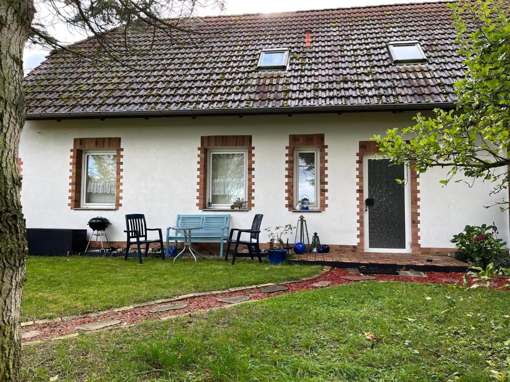 a white house with chairs and a table in the yard at Landurlaub Mecklenburgische Seenplatte B Waren Müritz in Schwarzenhof