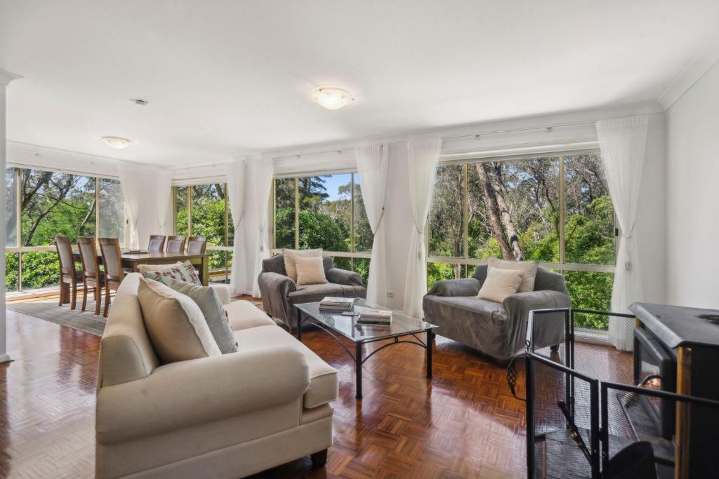 een woonkamer met banken, stoelen en ramen bij Fairway Getaway in Leura