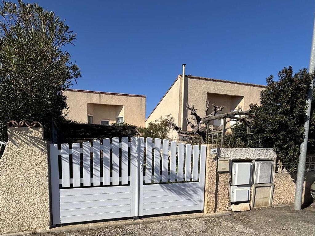 un portail blanc devant une maison dans l'établissement Maison confortable 8 personnes avec jardin, Port-la-Nouvelle - FR-1-229C-105, à Port-la-Nouvelle