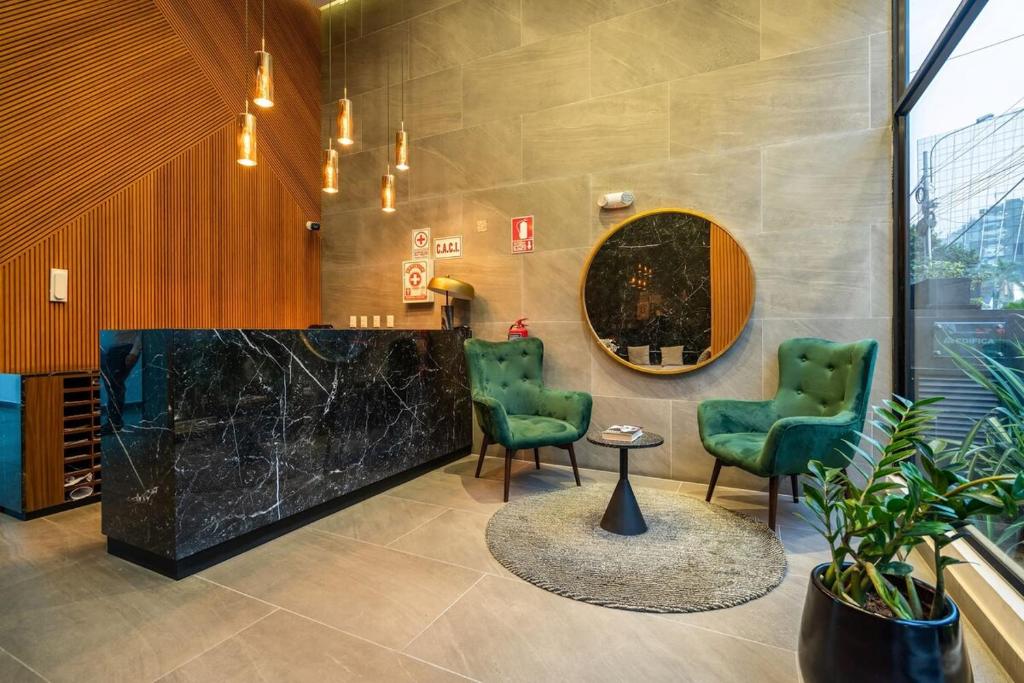 a lobby with two chairs and a table and a mirror at Alta Apartments by Geko in Lima