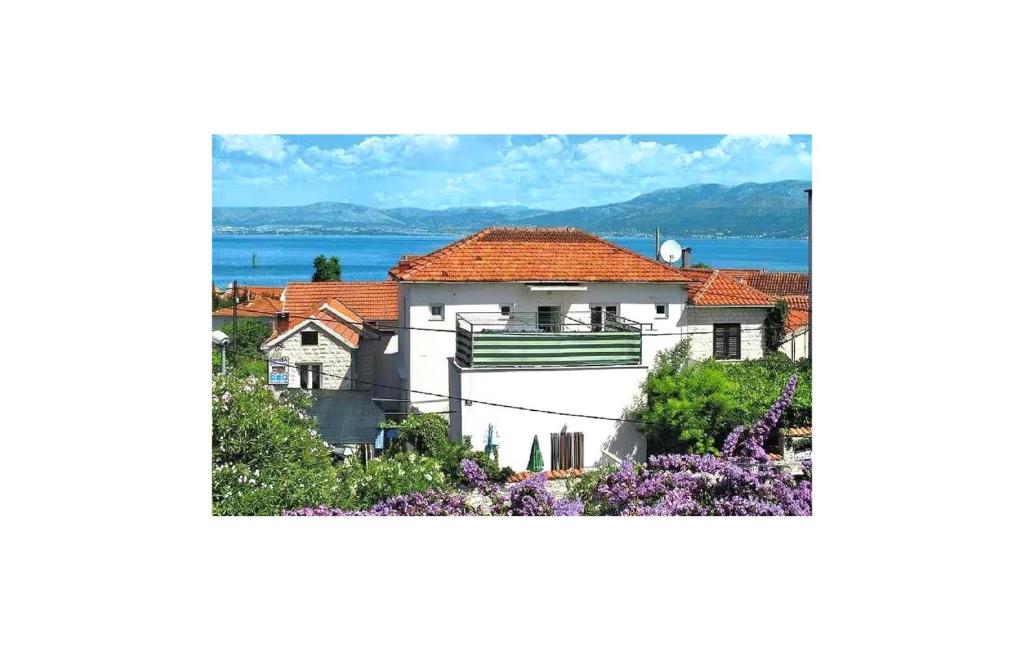 a white house with a red roof and some flowers at Stunning Apartment In Supetar With Wifi in Supetar