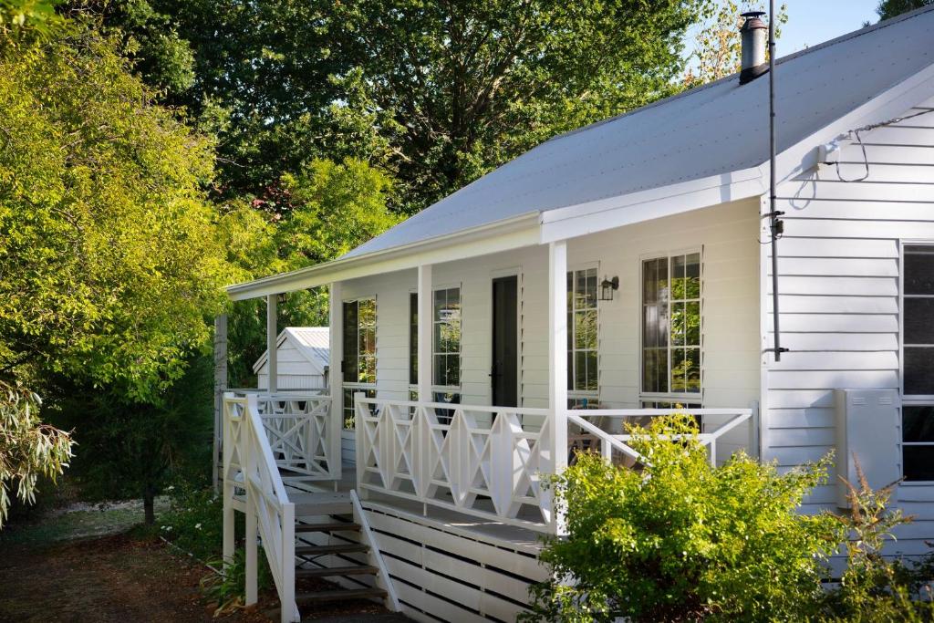 a white cottage with a large front porch at Springview Cottage- captivating bush retreat in Hepburn Springs