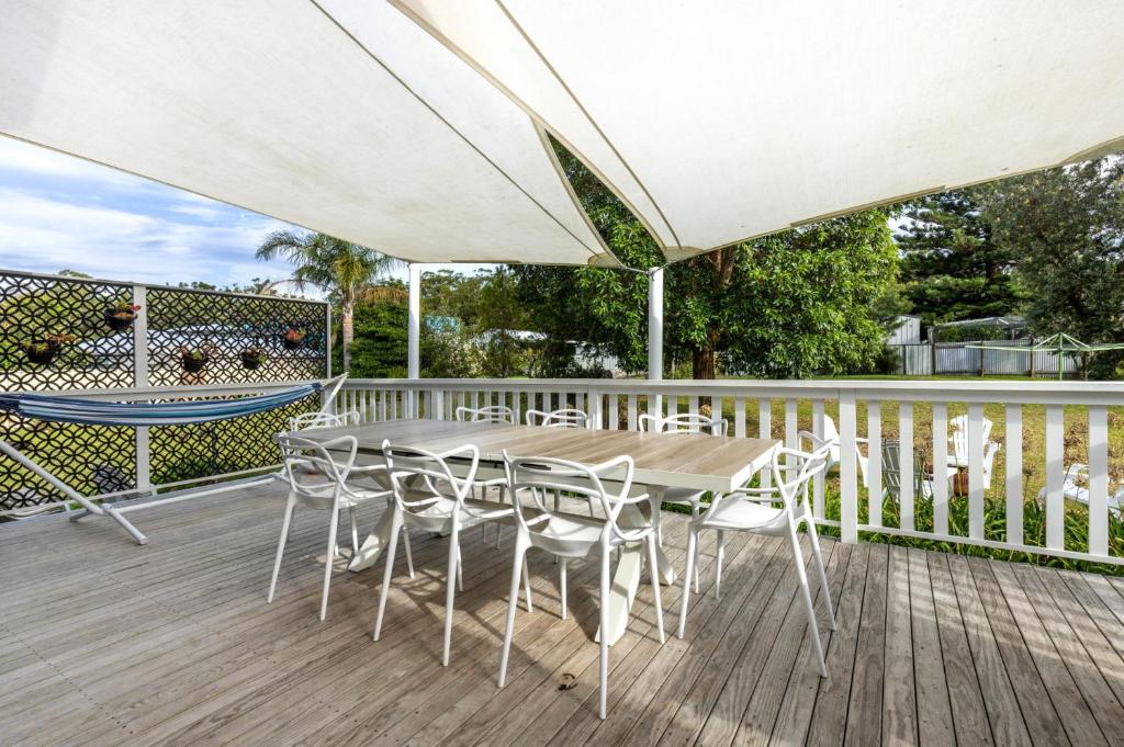 a table and chairs on a deck with an umbrella at Mar-Lins - Pet Friendly - 2 Mins Walk to Beach in Callala Beach