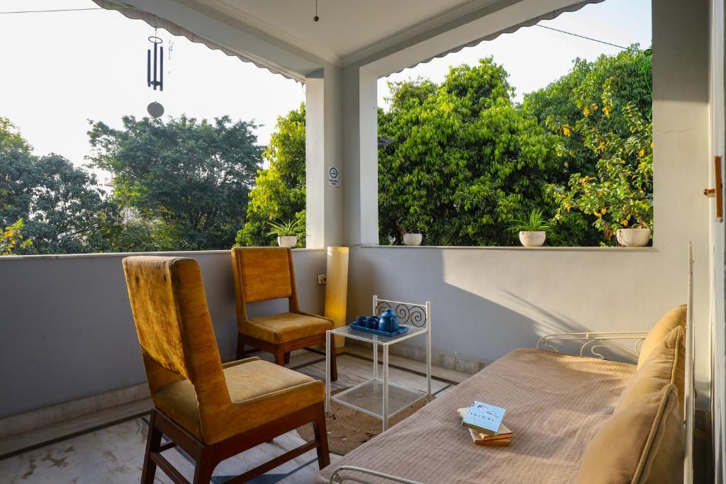 a room with a bed and two chairs on a balcony at Alaya Stays Anugrah Farm - 2 BHK Farmstay With Kids Room & Pvt Pool in Bahora