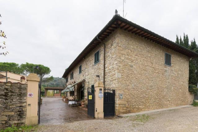 um grande edifício de tijolos com um portão em frente em La Fattoressa em Florença