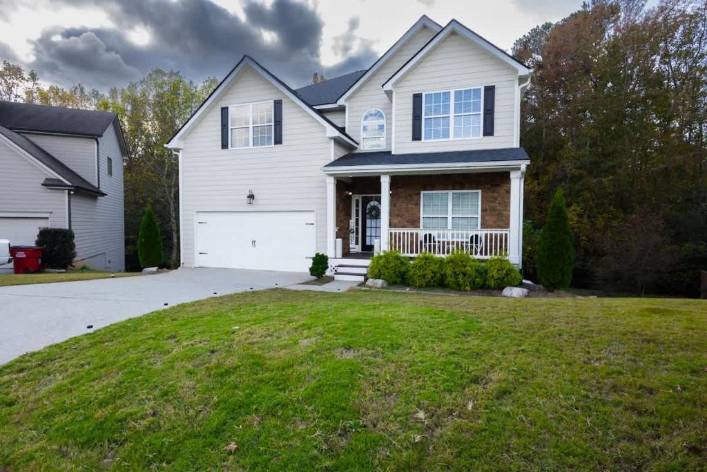 a white house with a garage and a grass yard at Large Rustic Family Home By RoadATL-KingBed-Firepit-Grill in Braselton