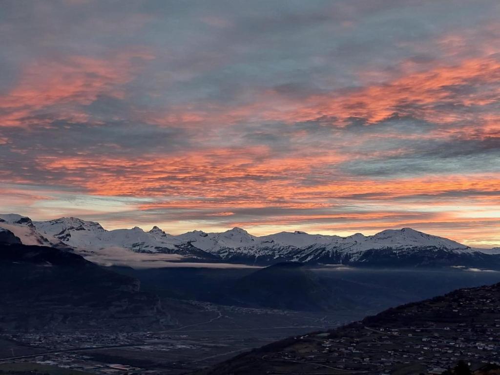 a sunset over a city with mountains and a lake at Family apartment with terrace in Veysonnaz