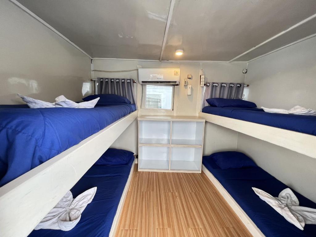 two beds in a small room with blue sheets at Bajo Familia Tour And Travel in Komodo Labuan Bajo Airport