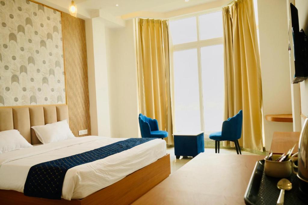 a hotel room with a bed and two blue chairs at Hotel JMS Grand in Jaunpur