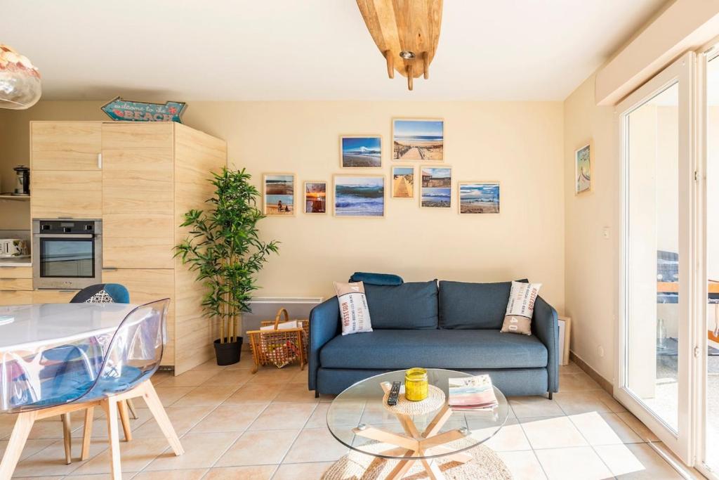 un salon avec un canapé bleu et une table dans l'établissement Beautiful apartment, terrace and garden, close to beaches, à Lit-et-Mixe