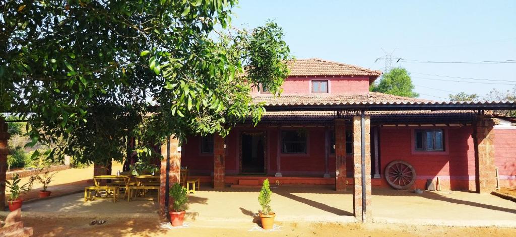 una casa roja con una mesa delante en OUR FARM Agro-Eco Tourism and Farm Stay, en Helwāk