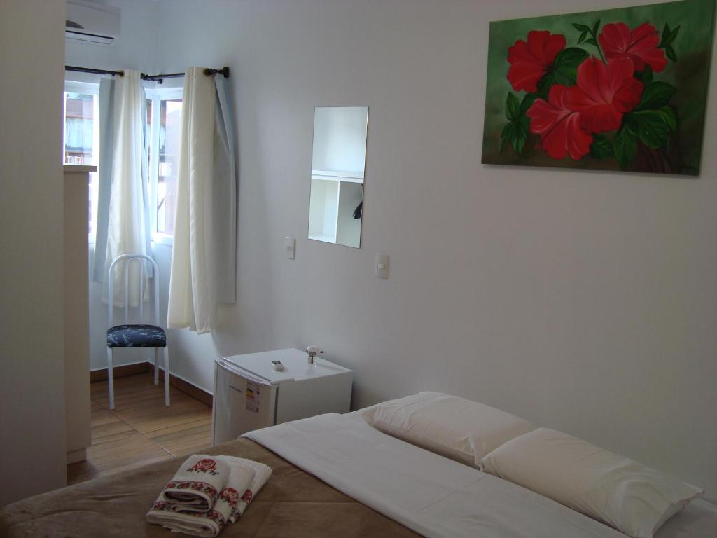 a bedroom with a bed and a painting on the wall at Pousada Amelia in Urubici