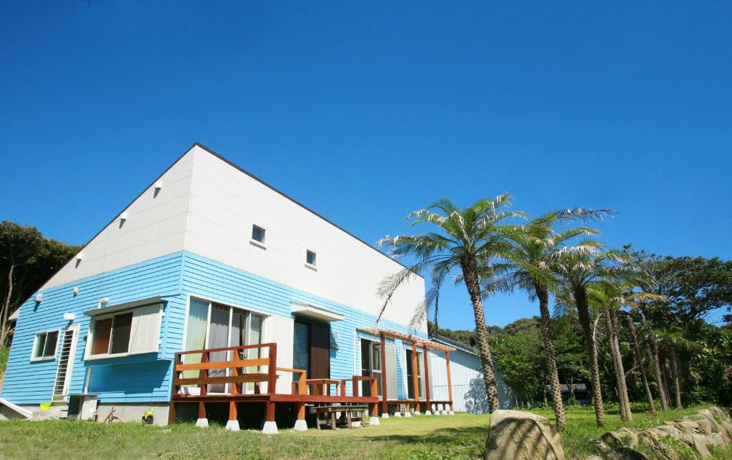 a blue and white house with palm trees at Tanegashima Minshuku Hapisuma in Minamitane