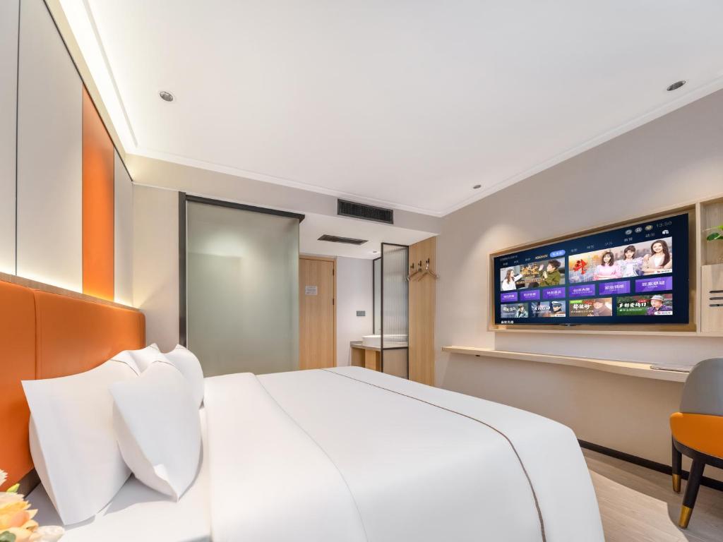 a bedroom with a white bed and a flat screen tv at Yiwu Yunjing Hotel in Yiwu