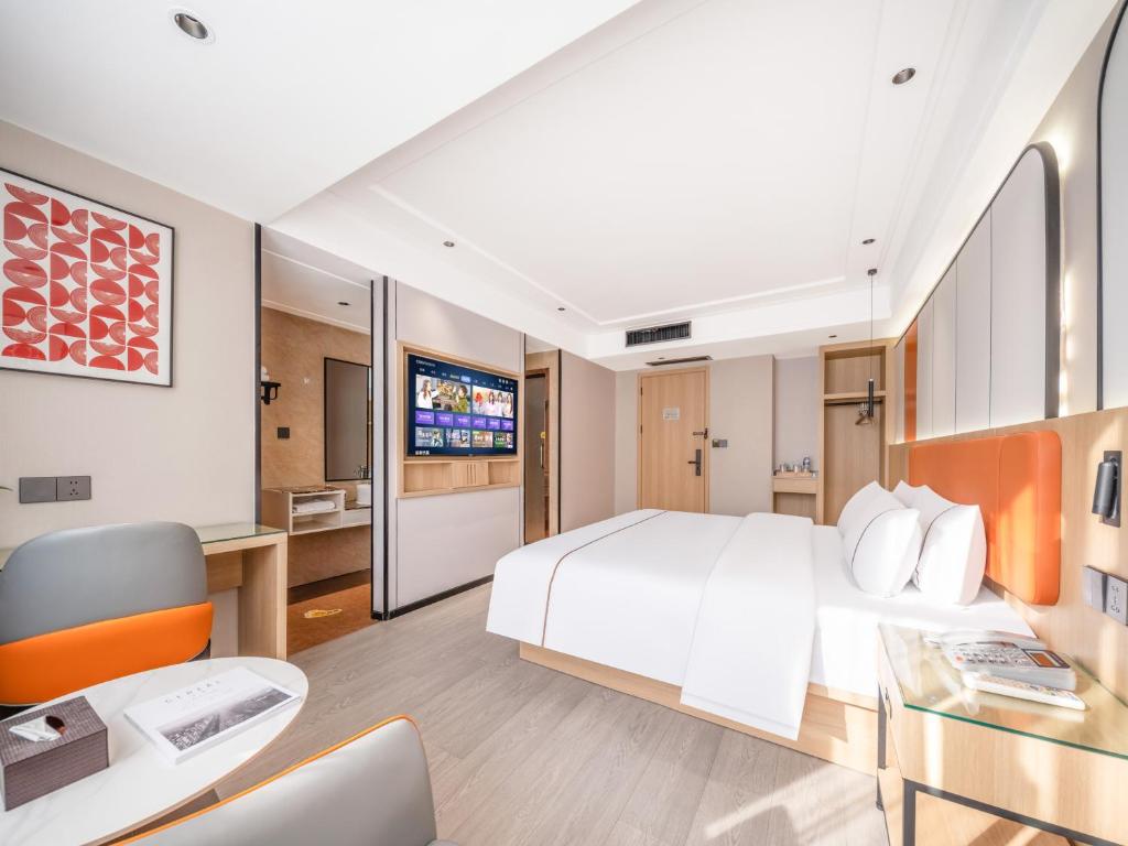a bedroom with a large white bed and a desk at Yiwu Yunjing Hotel in Yiwu