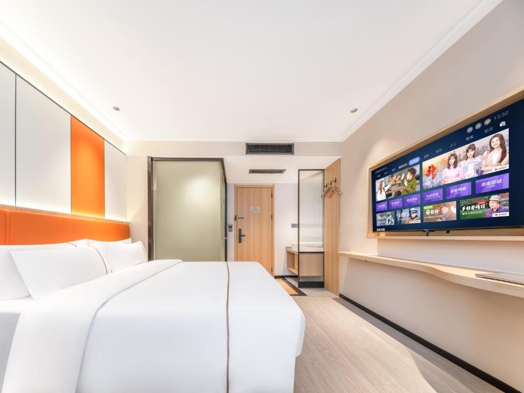 a hotel room with a bed and a flat screen tv at Yiwu Yunjing Hotel in Yiwu