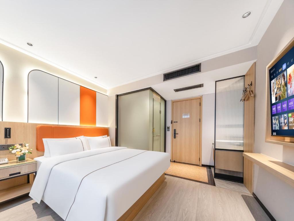 a bedroom with a large white bed and a flat screen tv at Yiwu Yunjing Hotel in Yiwu