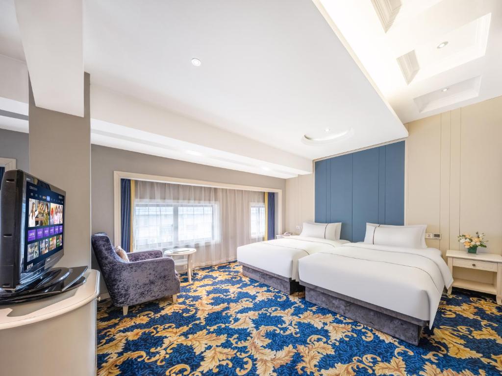a hotel room with two beds and a tv at Yiwu Yunjing Hotel in Yiwu