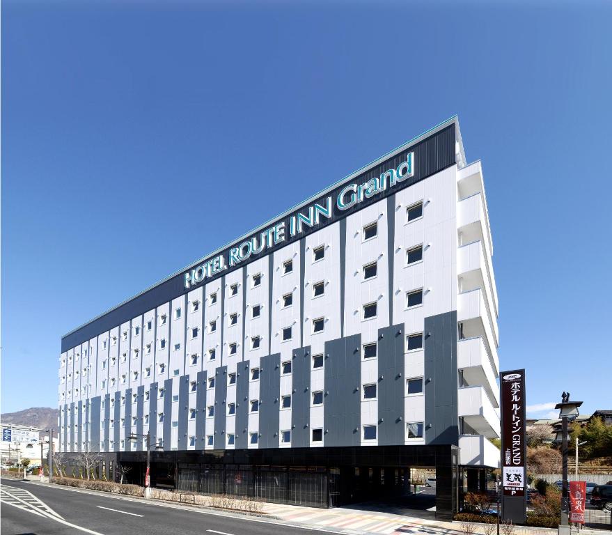 a large white building with a sign on it at Hotel Route Inn Grand Ueda Ekimae in Ueda