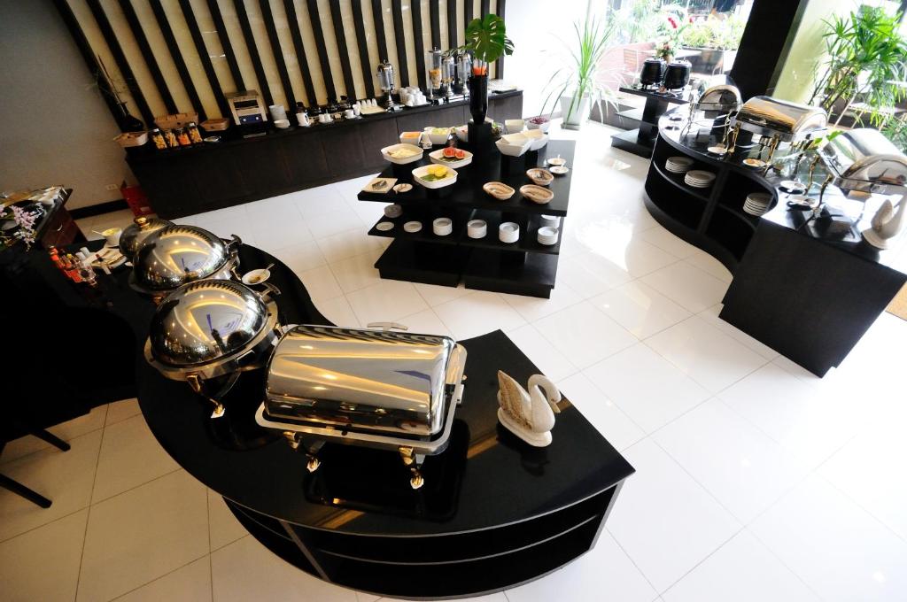 A buffet display with covered hot dishes, pastries and drink service.