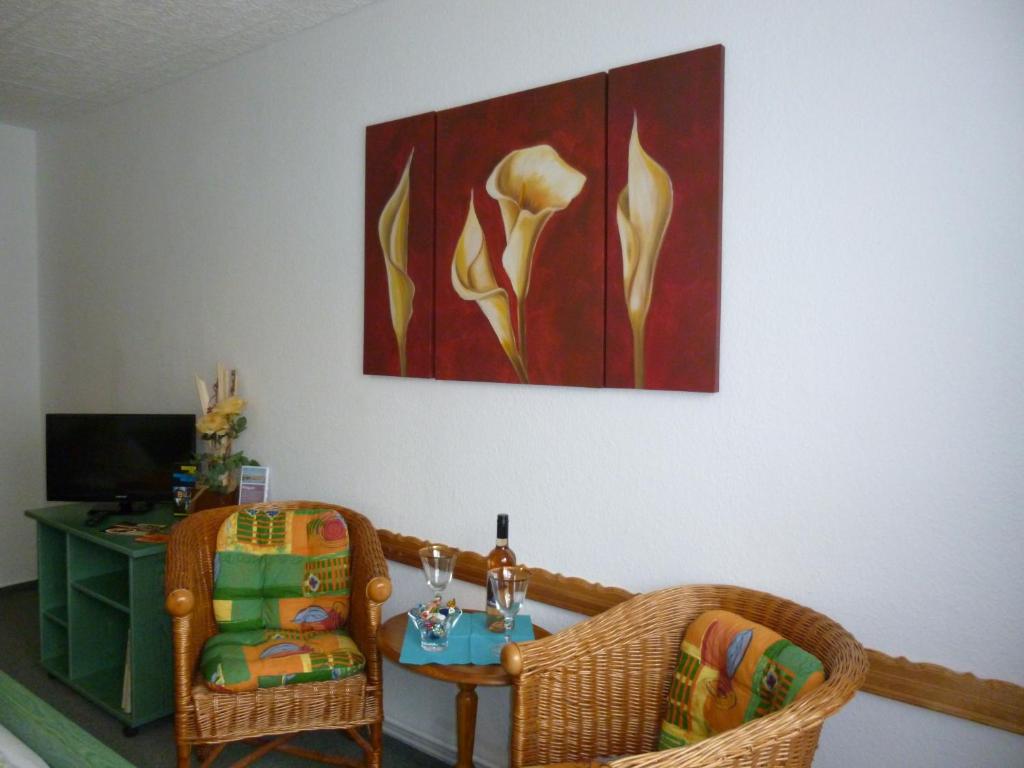 Pension am Peeneufer UG في فولغاست: غرفة معيشة مع طاولة وكراسي ولوحة