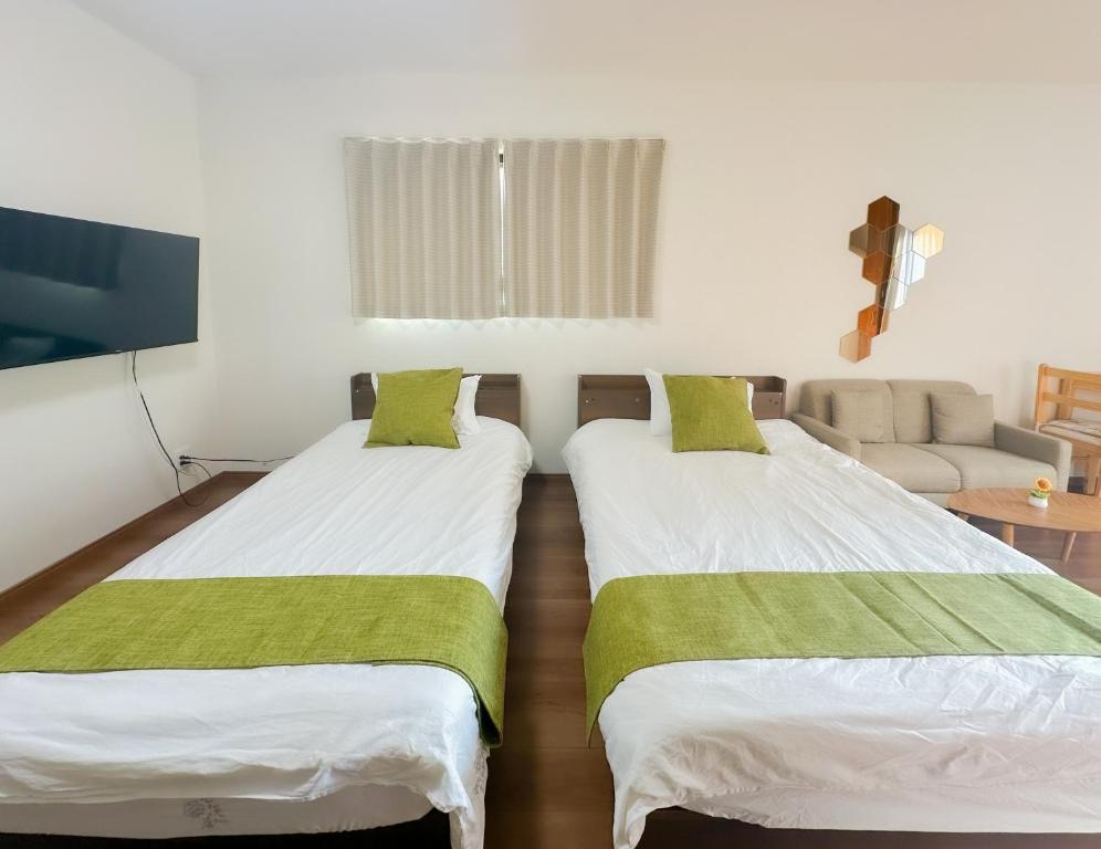 two twin beds in a room with a couch at HANASTAY花渓居 · 浦（URA) in Osaka