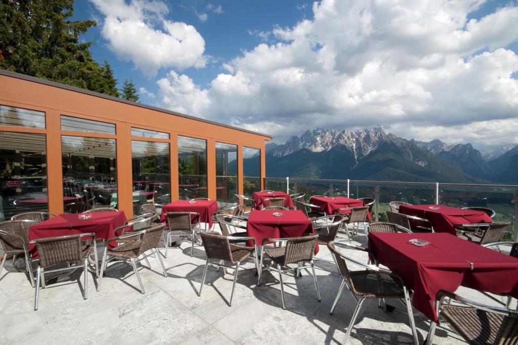 patio ze stołami i krzesłami z górami w tle w obiekcie Alpenhotel Ratsberg 1650m w mieście Dobbiaco