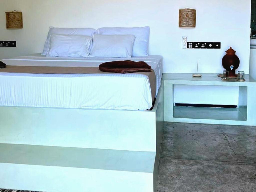 a bedroom with a white bed and two tables at Calma - Surf, Yoga & Coffee on a Private Beach in Dickwella