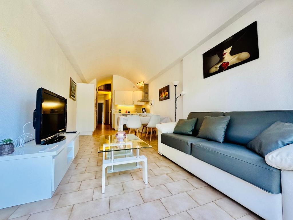 un salon avec un canapé bleu et une télévision dans l'établissement Le Velusine 2077 - Apt 4 Prs - parking - climatisation - piscine, à Antibes