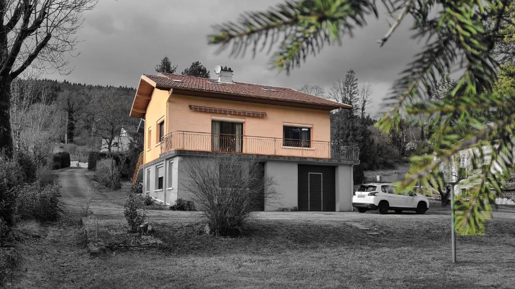 a small house with a balcony and a white car at Appartement dans maison au calme in Oyonnax
