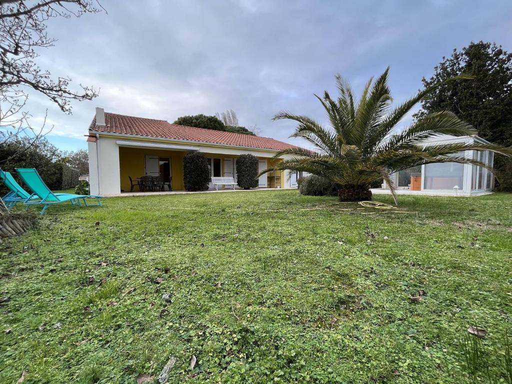 une maison avec un palmier dans la cour dans l'établissement Mais 5 pièces Oléron 10 couchages GRAND-VILLAGE-PLAGE GVO000-125, à Grand-Village-Plage