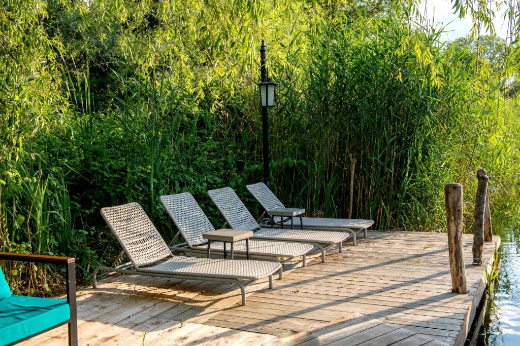 four chairs sitting on a wooden deck next to the water at Wineport Lodge Agva Riverside Hotel & Winery in Ağva