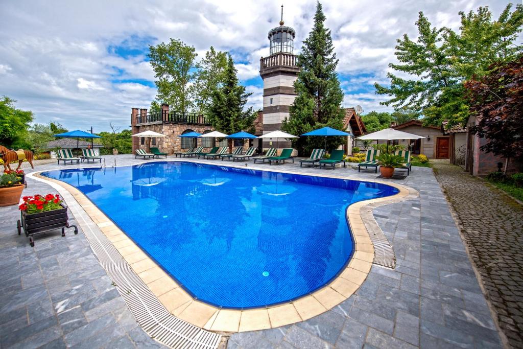 a pool at a resort with a lighthouse in the background at Wineport Lodge Agva Riverside Hotel & Winery in Ağva