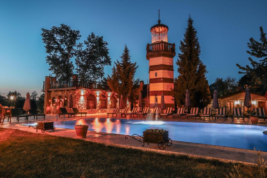 a lighthouse in front of a building with a pool at Wineport Lodge Agva Riverside Hotel & Winery in Ağva