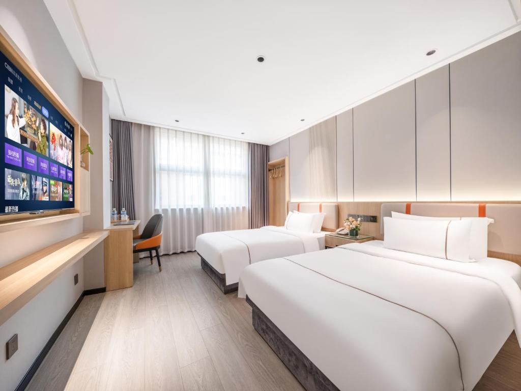 two beds in a hotel room with a flat screen tv at Yiwu Yunjing Hotel in Yiwu