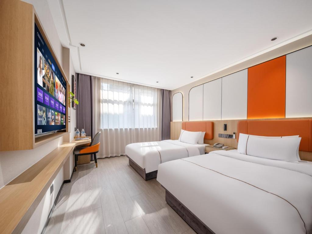 a hotel room with two beds and a flat screen tv at Yiwu Yunjing Hotel in Yiwu