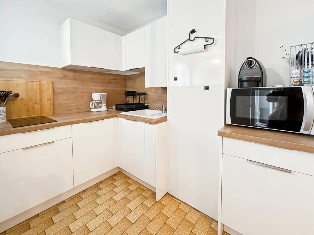 une cuisine avec des armoires blanches et un micro-ondes dans l'établissement Bel appartement T2 avec parking au Cap d'Agde - FR-1-749-86, au Cap d'Agde