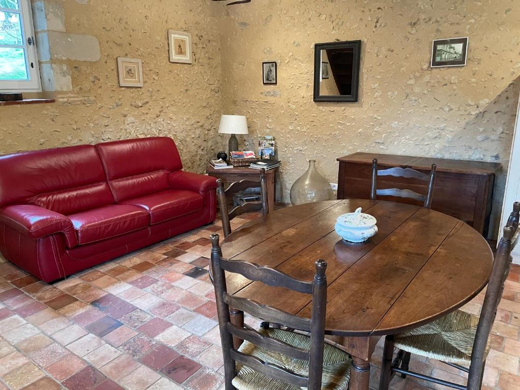 - un salon avec une table en bois et un canapé rouge dans l'établissement Charme campagnard proche ville, jardin paisible - FR-1-410-468, à La Flèche