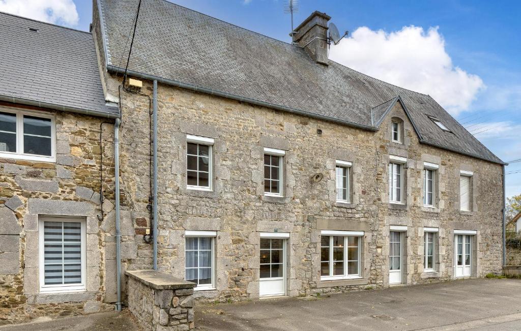 an old stone building with white windows and a roof at Lovely Home In Hauteville-Sur-Mer in Hauteville-sur-Mer
