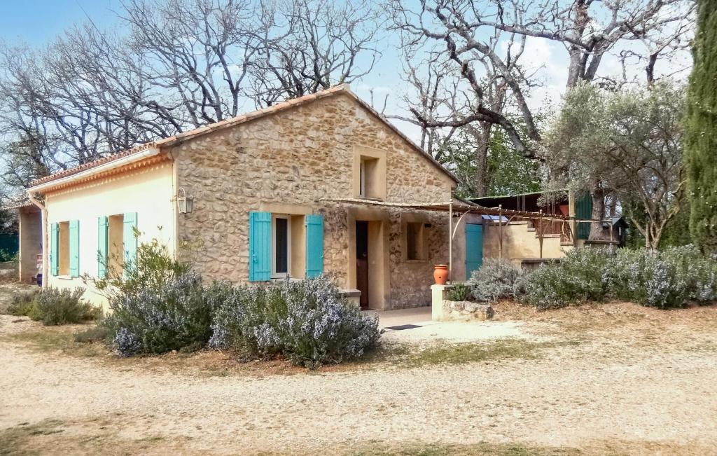 une maison en pierre avec volets bleus dans une cour dans l'établissement Charmante Maison Vue Montagne, à Oppède