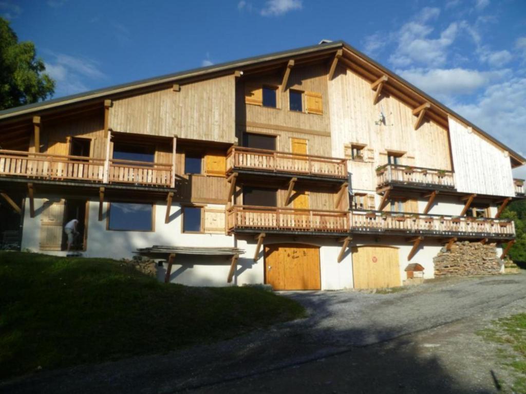 - un grand bâtiment avec des balcons en bois sur le côté dans l'établissement La dent de Cons, à Notre-Dame-de-Bellecombe