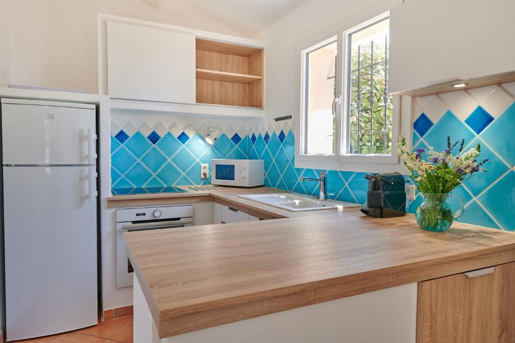 a kitchen with blue tiled walls and a white refrigerator at Résidence Belvedere de Palombaggia in Porto-Vecchio